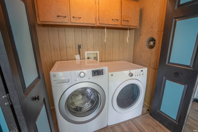 laundry room featuring washer and dryer, cabinet space, wood finished floors, and wood walls