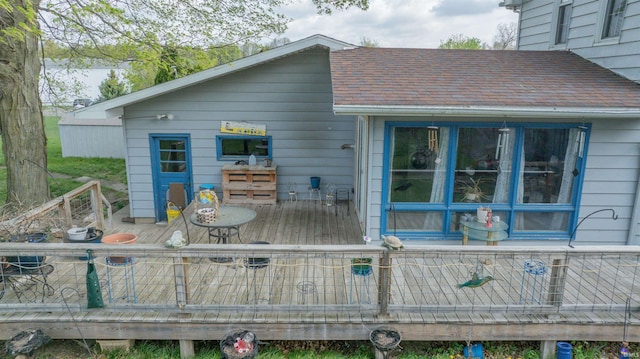 back of house featuring a deck and roof with shingles
