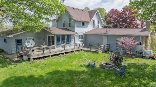 rear view of property featuring a yard, a deck, and a shingled roof