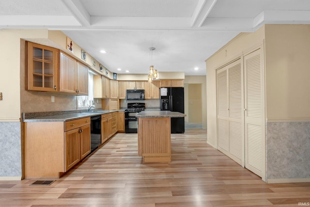 kitchen featuring black appliances, light wood-style flooring, a sink, beam ceiling, and a center island