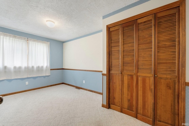 unfurnished bedroom with carpet floors, baseboards, a closet, and a textured ceiling