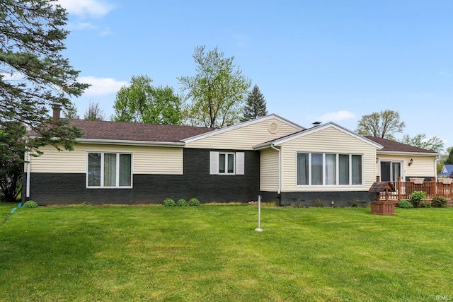 view of front facade featuring brick siding, a wooden deck, and a front yard