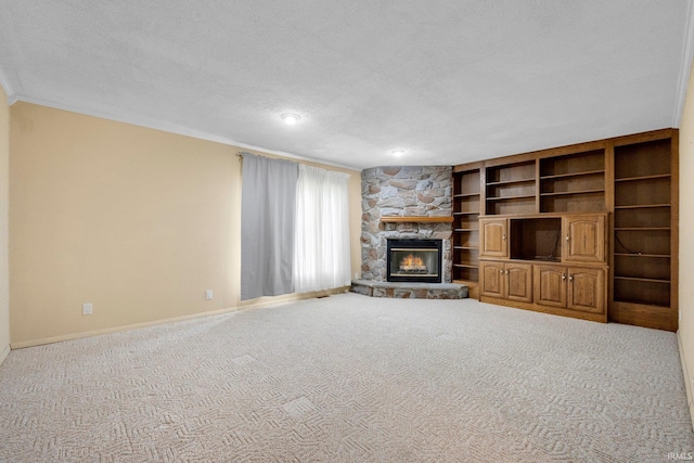 unfurnished living room featuring baseboards, a fireplace, crown molding, carpet floors, and a textured ceiling