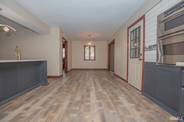 6318 Peacock Ln, Evansville, IN 47715 - empty room featuring a chandelier, wood finished floors, baseboards, and a sink
