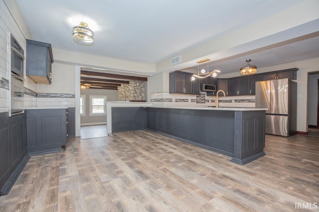 6318 Peacock Ln, Evansville, IN 47715 - kitchen with appliances with stainless steel finishes, light countertops, decorative backsplash, wood finished floors, and ceiling fan