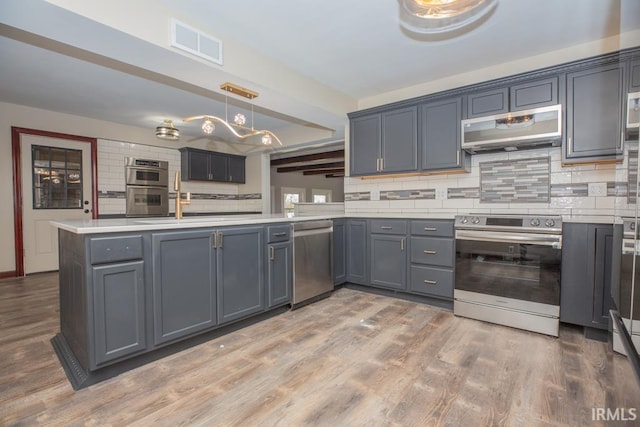 6318 Peacock Ln, Evansville, IN 47715 - kitchen featuring stainless steel appliances, decorative backsplash, a peninsula, light wood-type flooring, and gray cabinetry
