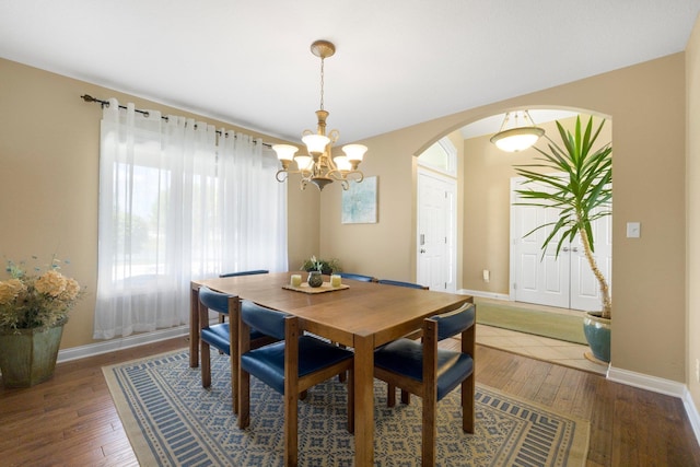 3090 Kellygreen Dr, Angola, IN 46703 - dining room featuring arched walkways, a chandelier, hardwood / wood-style floors, and baseboards