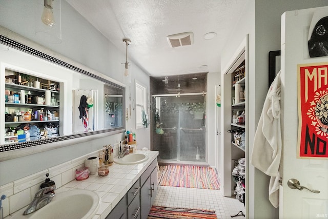 full bathroom featuring a stall shower, double vanity, tile patterned flooring, and a textured ceiling