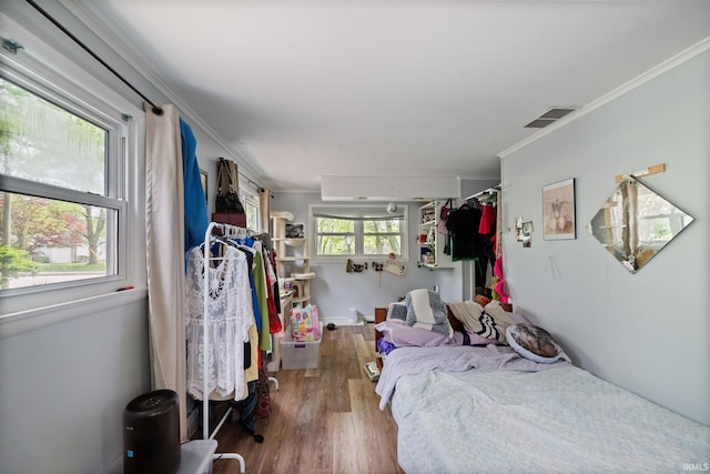 bedroom with wood finished floors and crown molding