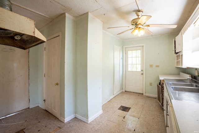 kitchen featuring crown molding, a sink, light countertops, ceiling fan, and white cabinets