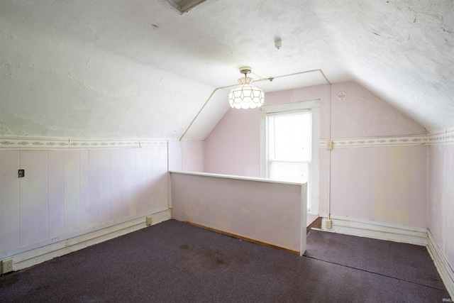bonus room featuring lofted ceiling, carpet floors, and wooden walls