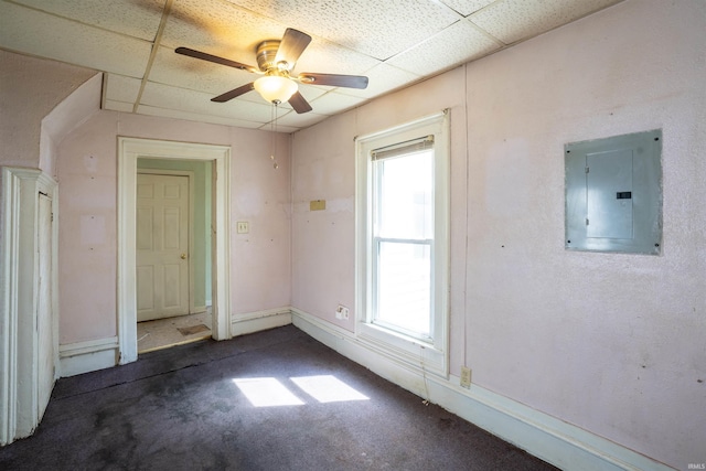 carpeted empty room with electric panel, a paneled ceiling, a ceiling fan, and baseboards