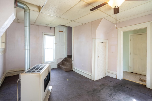 carpeted spare room featuring a drop ceiling, a ceiling fan, and baseboards