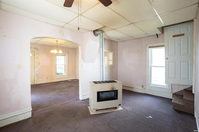 spare room featuring heating unit, carpet flooring, arched walkways, a drop ceiling, and a chandelier