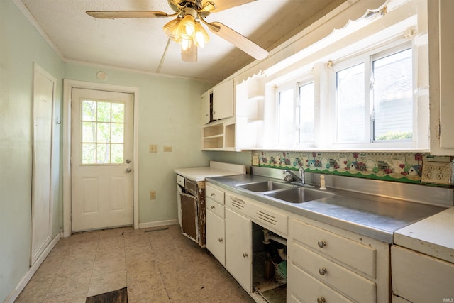 kitchen featuring a sink, stainless steel counters, white cabinetry, baseboards, and open shelves