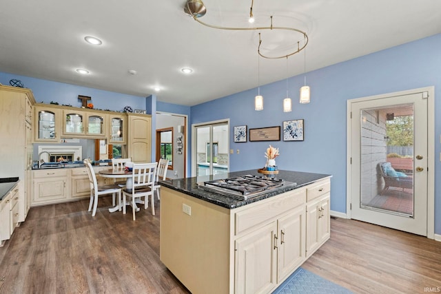 15 Saint Emily Dr, Huntington, IN 46750 - kitchen featuring stainless steel gas stovetop, dark wood-type flooring, a center island, glass insert cabinets, and pendant lighting