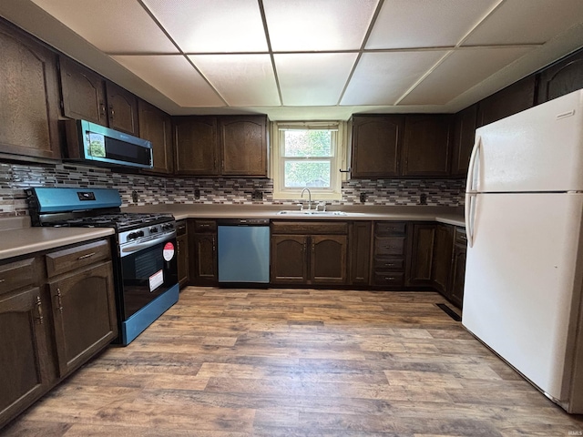 919 Kensington Blvd, Fort Wayne, IN 46805 - kitchen featuring stainless steel appliances, a sink, dark brown cabinets, light wood-type flooring, and a drop ceiling