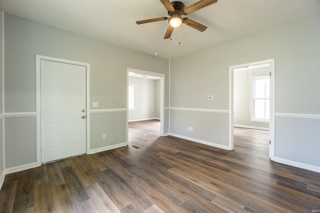 spare room with a ceiling fan, dark wood-style floors, and baseboards