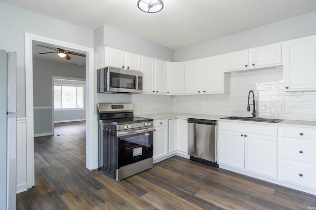 kitchen featuring appliances with stainless steel finishes, a sink, backsplash, a ceiling fan, and a textured ceiling