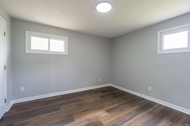 unfurnished room featuring healthy amount of natural light, dark wood-type flooring, baseboards, and a textured ceiling