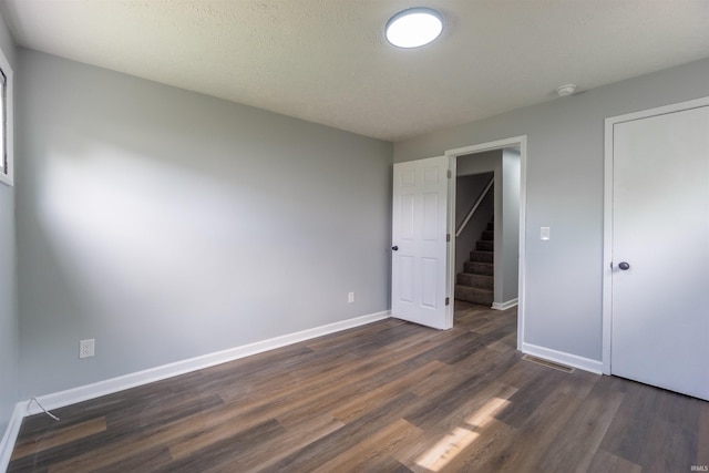 unfurnished bedroom with dark wood-type flooring and baseboards
