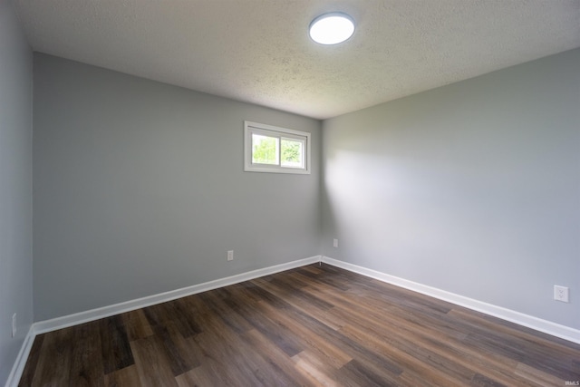 unfurnished room featuring dark wood-type flooring, baseboards, and a textured ceiling