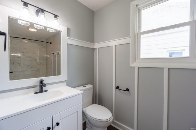 bathroom featuring toilet, vanity, and a shower