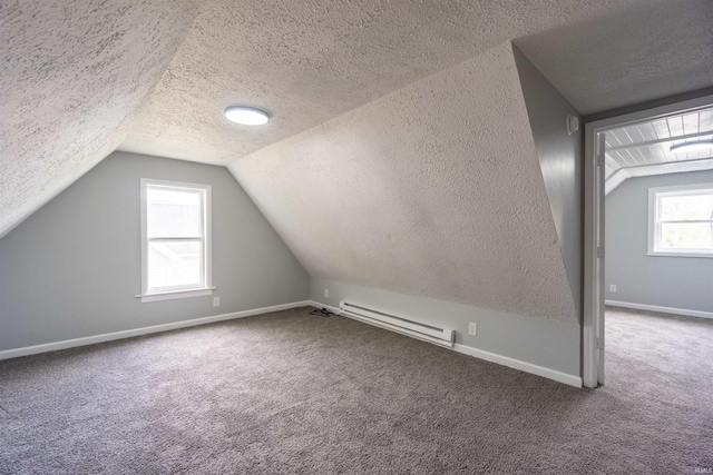 additional living space with a baseboard radiator, a textured ceiling, vaulted ceiling, carpet, and baseboards