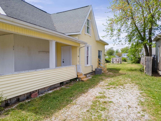 view of property exterior with a shingled roof, central air condition unit, and fence