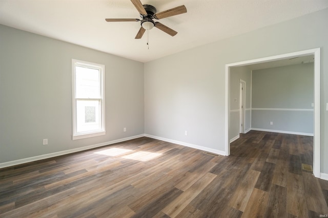 spare room with a ceiling fan, dark wood-style floors, and baseboards
