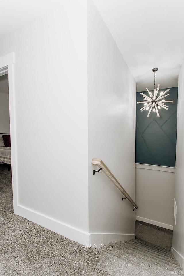 staircase with a chandelier, carpet, and baseboards