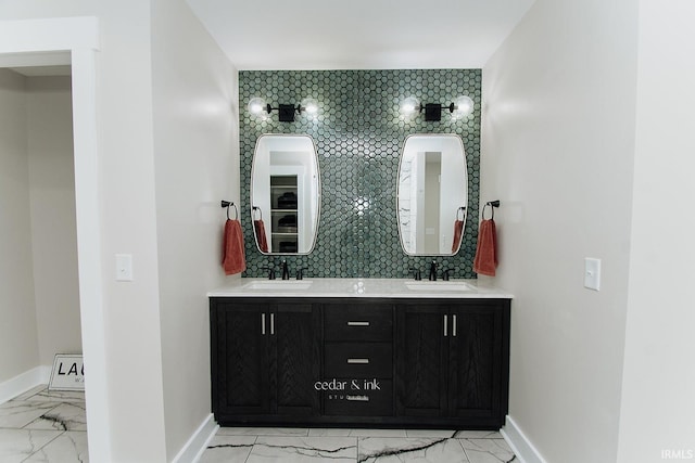 bathroom with marble finish flooring, baseboards, double vanity, and tasteful backsplash