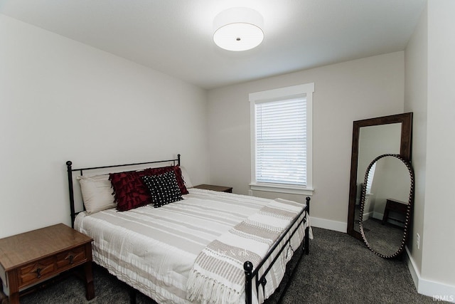 bedroom with dark carpet and baseboards
