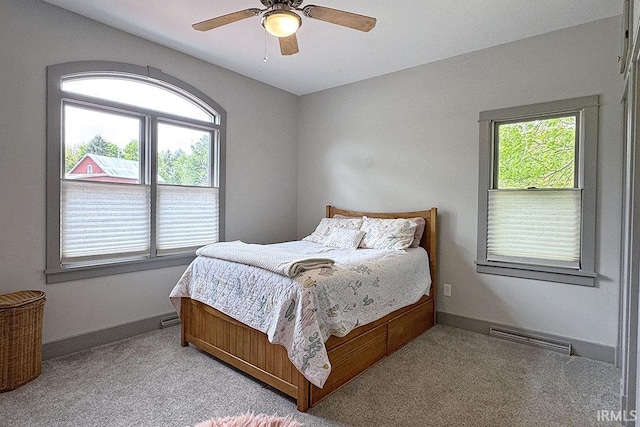 bedroom with multiple windows, light carpet, and baseboards