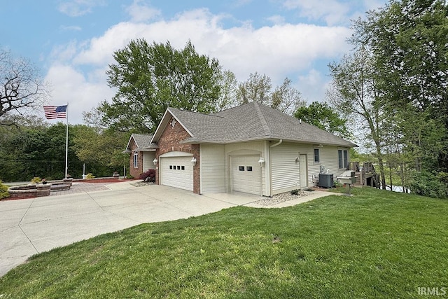 view of side of home with central air condition unit, a lawn, a shingled roof, an attached garage, and concrete driveway