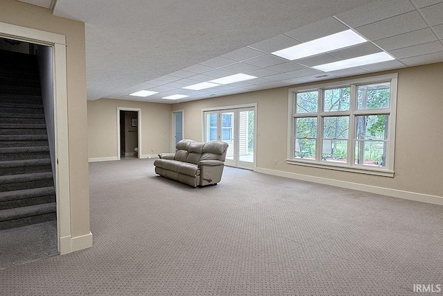 carpeted living room featuring baseboards and stairs