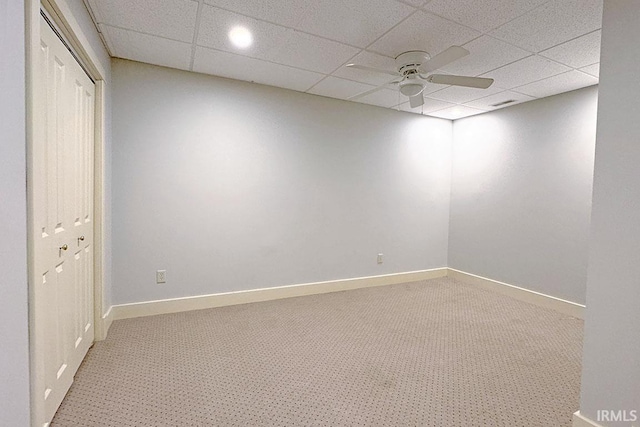empty room with ceiling fan, light carpet, a paneled ceiling, and baseboards