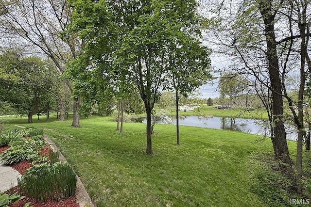 view of green lawn featuring a water view