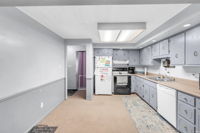 kitchen featuring white appliances, gray cabinetry, a sink, under cabinet range hood, and light countertops