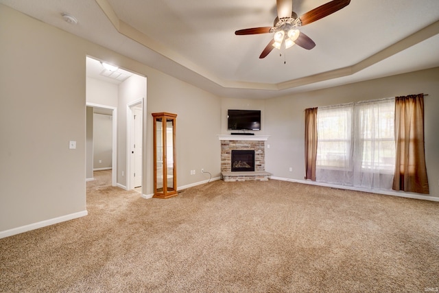 1592 Breckenridge Pass, Fort Wayne, IN 46845 - unfurnished living room with a tray ceiling, ceiling fan, carpet, a stone fireplace, and baseboards
