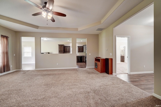 1592 Breckenridge Pass, Fort Wayne, IN 46845 - unfurnished living room featuring light colored carpet, a raised ceiling, a ceiling fan, and baseboards