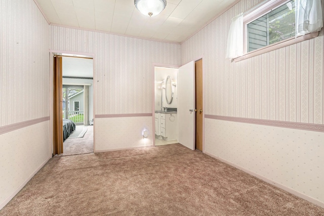 unfurnished room featuring crown molding, wallpapered walls, and carpet