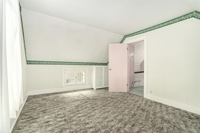 carpeted spare room with vaulted ceiling and baseboards