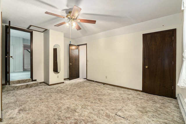 unfurnished bedroom featuring carpet, a baseboard heating unit, baseboards, and a ceiling fan
