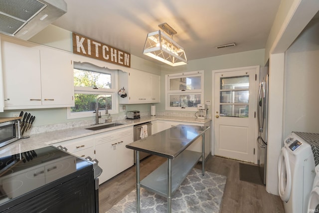 kitchen with a sink, washer / clothes dryer, appliances with stainless steel finishes, dark wood finished floors, and light countertops