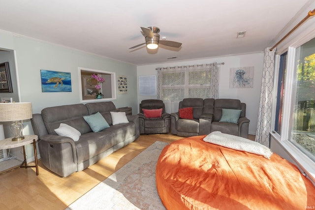 living room with wood finished floors, ceiling fan, and crown molding