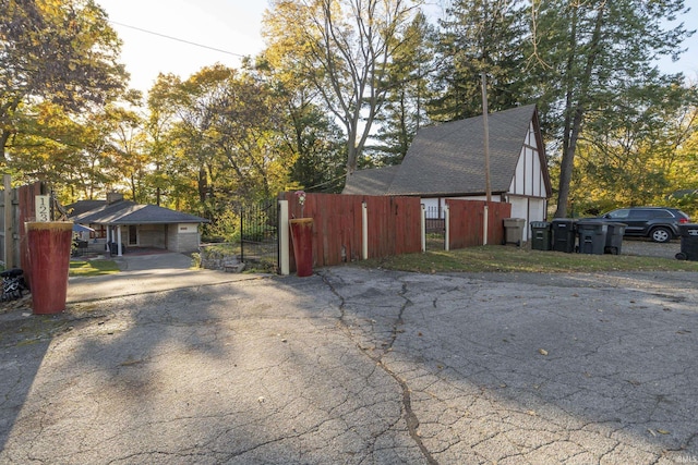 view of home's exterior with fence, a gate, asphalt driveway, and a shingled roof