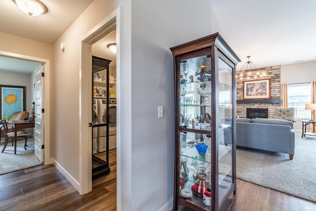 corridor with dark wood finished floors, washing machine and clothes dryer, and baseboards