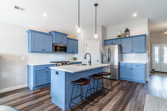 kitchen with appliances with stainless steel finishes, a sink, blue cabinetry, vaulted ceiling, and recessed lighting