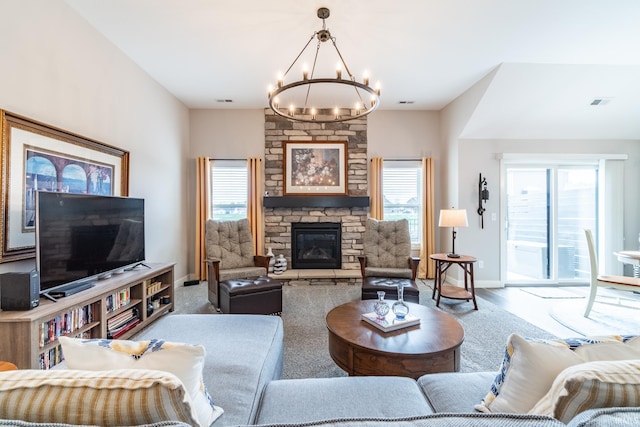 living room with a chandelier, a stone fireplace, and baseboards